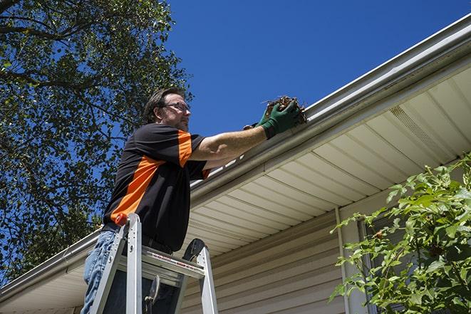 workman on a ladder repairing a broken gutter in Allegan MI